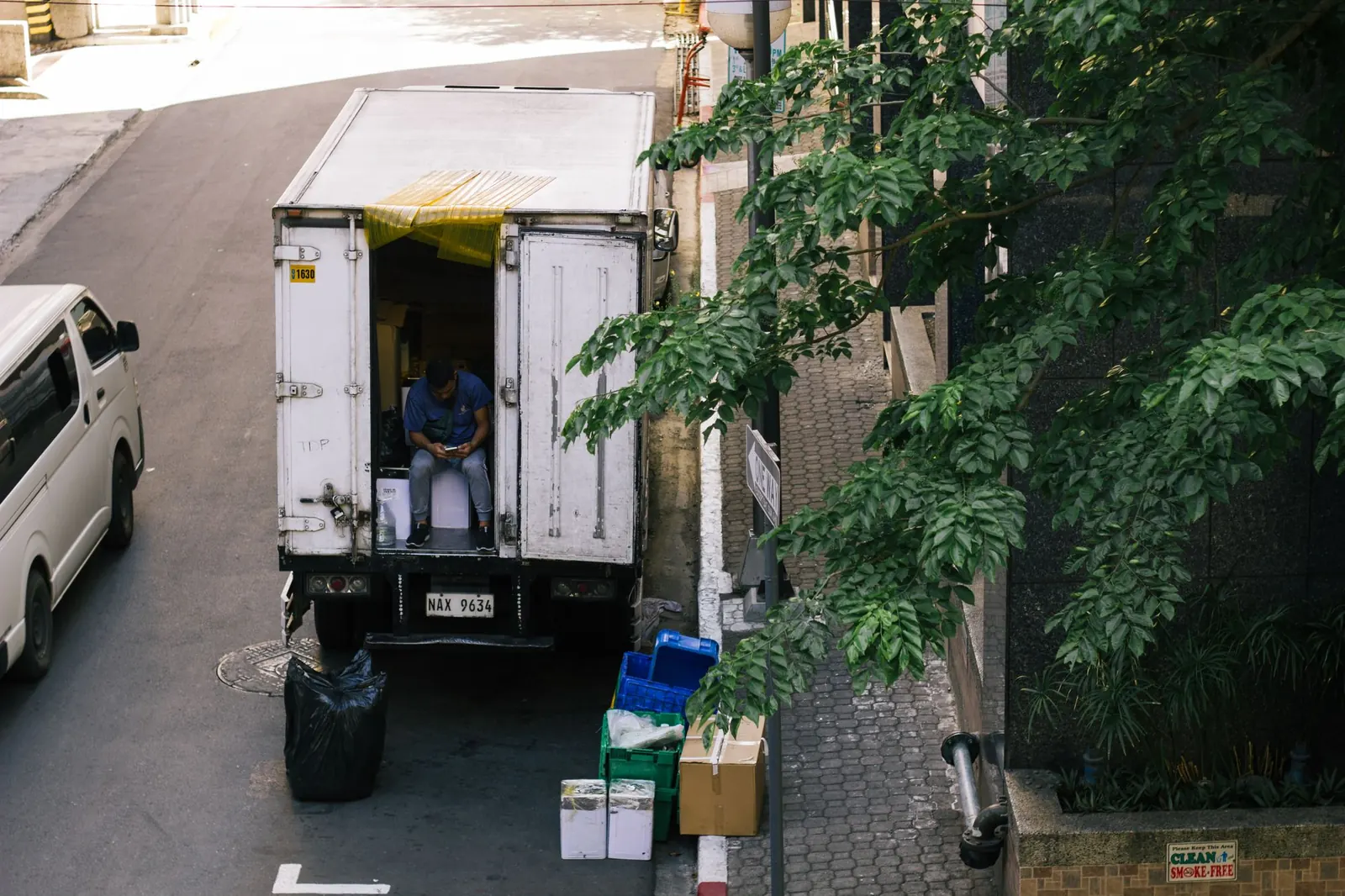 Trabalhador sentado na porta de um caminhão de carga numa rua